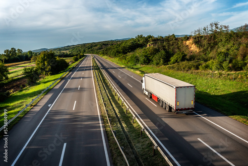 Tablou pe pânză Truck with semi-trailer driving along highway on the sunset background