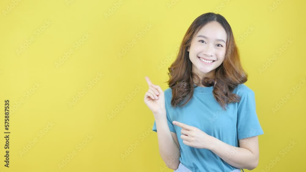 Asian girl pointing online billboard in yellow background Asian girl pointing online billboard in yellow background