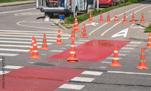 Red cones on pedestrian crossing. Road repairs, fences.