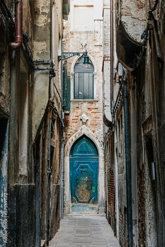 Venice Italy old antique buildings in warm yellow and sand tones with green, teal and turquoise doors and windows.