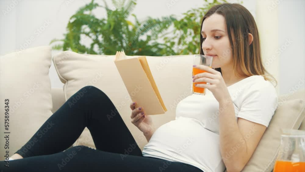 4k slowmotion video of pregnant woman drinking orange juice and reading a book. 4k slowmotion video of pregnant woman drinking orange juice and reading a book.