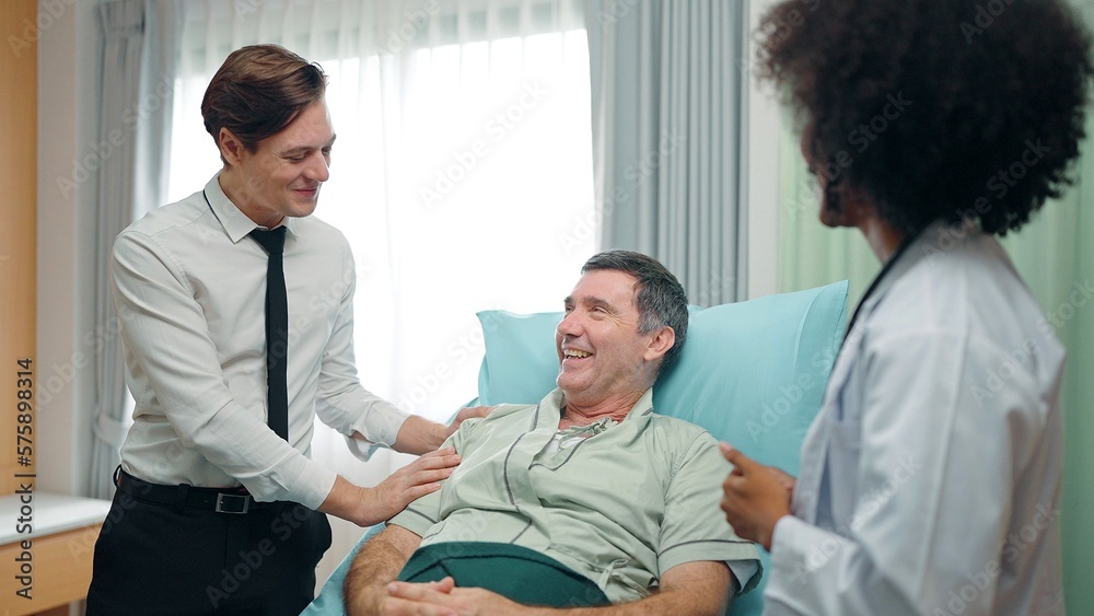 Obraz premium A happy son visits a recovering old father lying on the bed in hospital. and they talked with doctor