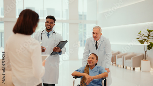 Two multiracial doctors are taking African patient who sitting on a wheelchair to hospital reception to take her history. A female patient receive care from male and female physicians at the hospital.
