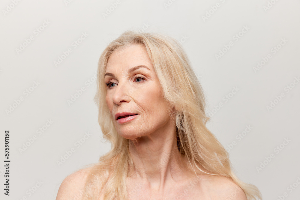 Portrait of beautiful middle-aged woman with well-kept healthy skin over grey studio background. Mature old lady. Concept of natural beauty, face skin care, cosmetology and cosmetics, health Portrait of beautiful middle-aged woman with well-kept healthy skin over grey studio background. Mature old lady. Concept of natural beauty, face skin care, cosmetology and cosmetics, health
