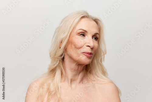 Beauty of age. Portrait of beautiful middle-aged  mature woman with well-kept natural skin posing over grey background. Concept of natural beauty  face skin care  cosmetology and cosmetics  health