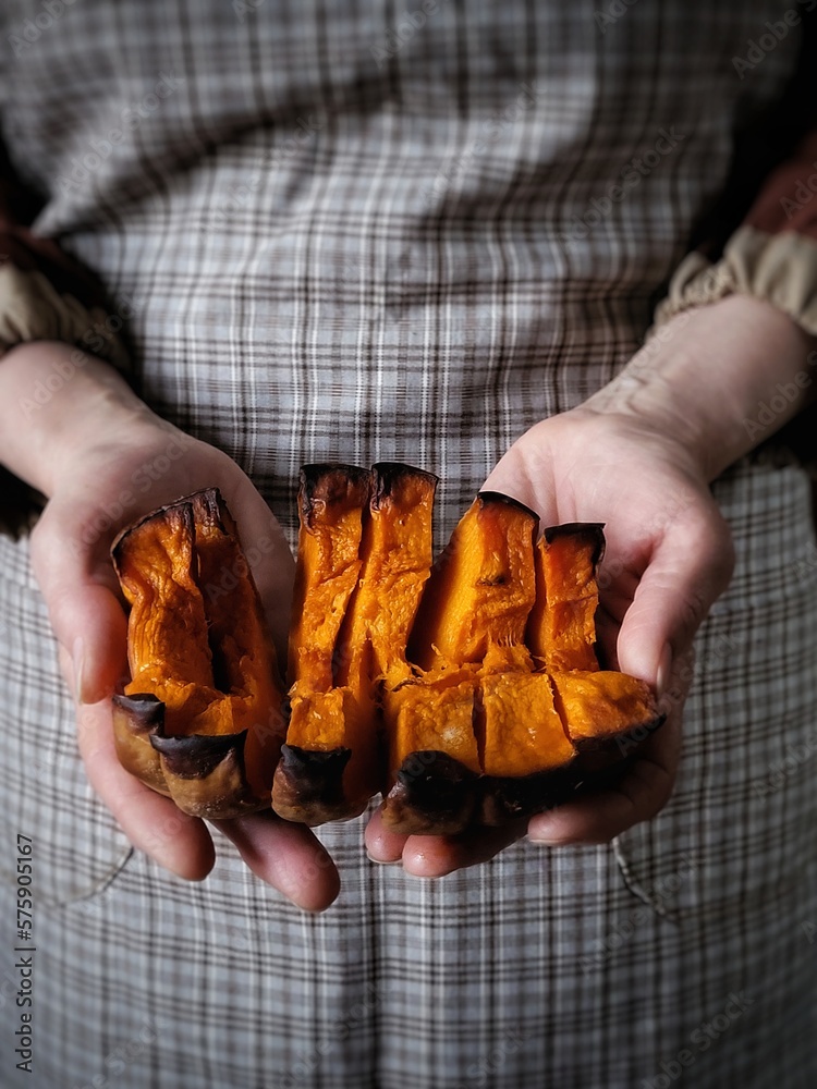 Baked caramelized pumpkin in the hands of a woman. A person in a rustic apron holds slices of fried pumpkin. Useful cooking. Healthy eating. Baked caramelized pumpkin in the hands of a woman. A person in a rustic apron holds slices of fried pumpkin. Useful cooking. Healthy eating.