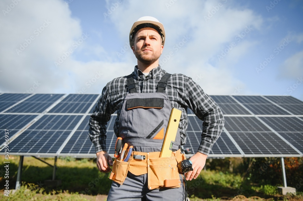 Male worker in uniform outdoors with solar batteries at sunny day. Male worker in uniform outdoors with solar batteries at sunny day.