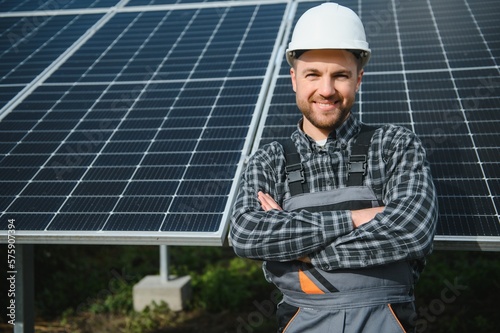 A handyman standing on the rooftop with solar panels and smiling at the camera.