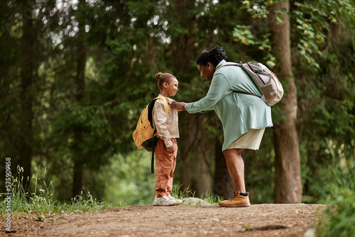 Side view portrait of black mother and daughter hiking together with backpacks and enjoying nature