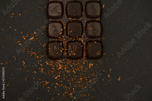 Bitter chocolate bar on a black paper background, close-up. View from above