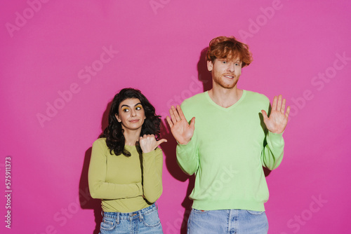 White young woman pointing at redhead man posing at camera