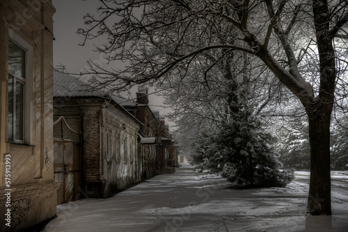 Winter night in an alley of a provincial town, after the snowfall has ended.