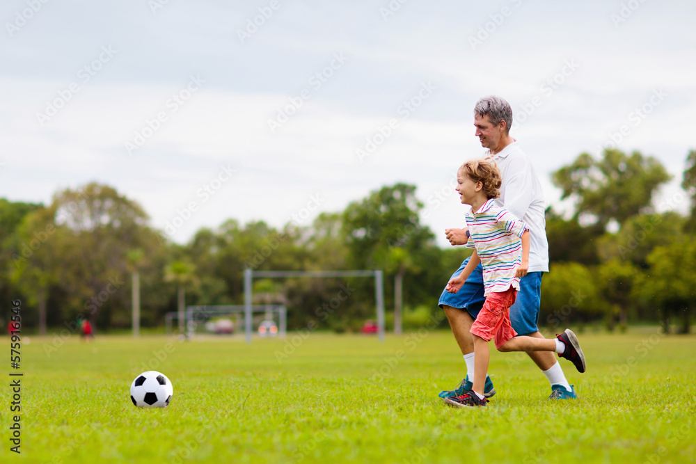 Obraz premium Father and son play football. Dad and kid run.