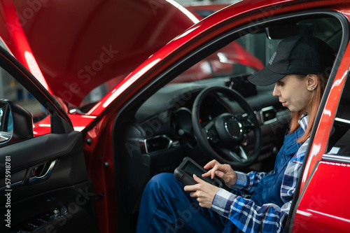 Caucasian female auto mechanic uses a special computer to diagnose faults. 