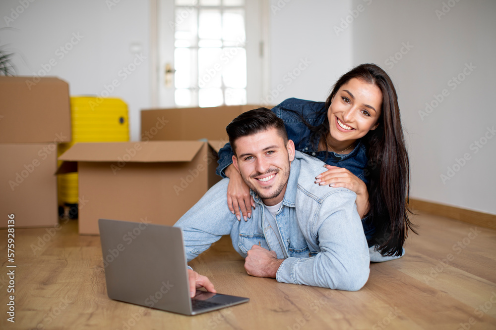 Young Happy Couple Using Laptop After Moving In New House Young Happy Couple Using Laptop After Moving In New House