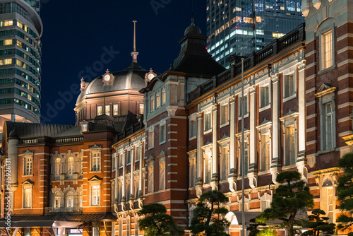 日本 東京都千代田区丸の内のライトアップされた赤レンガ作りの東京駅舎と高層ビル群の夜景