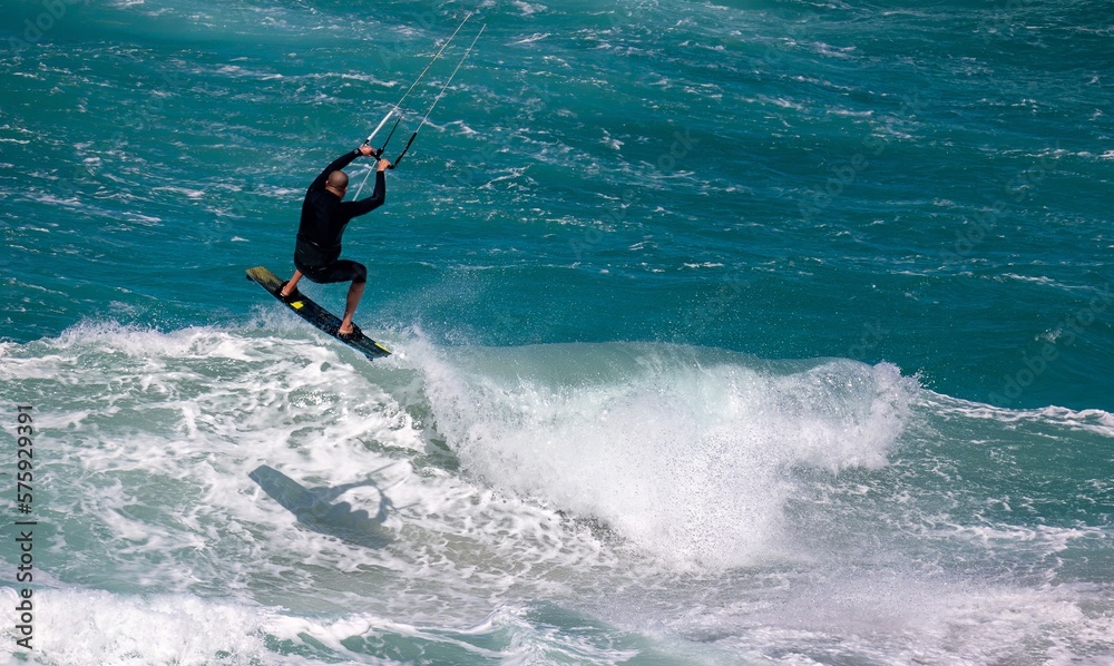Kiteboarder jumps a wave