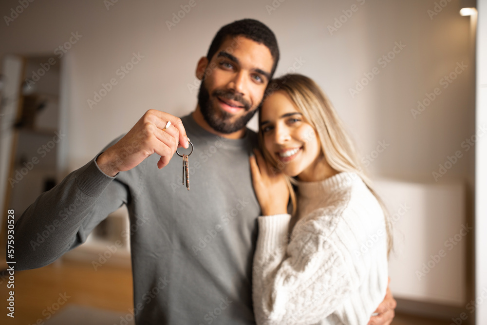 Cheerful young arab man hugging european wife, show keys, enjoy new home, celebration rental property Cheerful young arab man hugging european wife, show keys, enjoy new home, celebration rental property