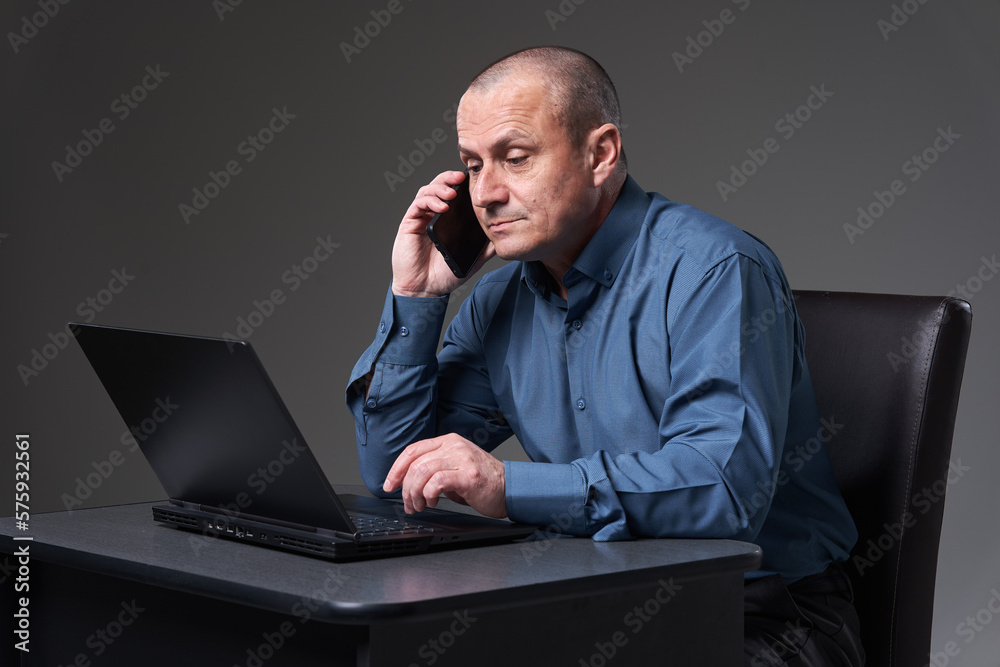 Mature businessman multitasking with phone and laptop Mature businessman multitasking with phone and laptop