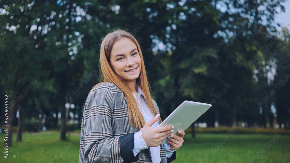 A young girl walks with a tablet in the park. A young girl walks with a tablet in the park.