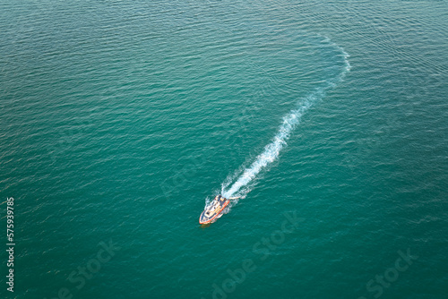 Aerial view of white yacht swimming on sea waves with ripple surface. Motor boat in motion on ocean