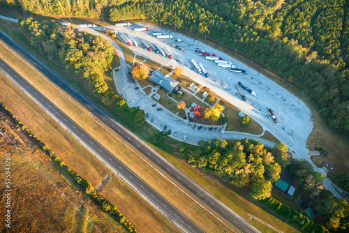 View from above of big parking rest area for cars and trucks near busy american highway with fast moving traffic. Recreational place during interstate travel