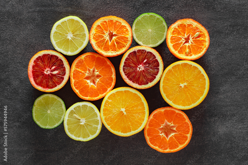 Citrus fruits cut in half, oranges, tangerines, lemons, limes on dark background, top view Citrus fruits cut in half, oranges, tangerines, lemons, limes on dark background, top view