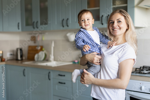 a woman holds a baby in her arms in the kitchen