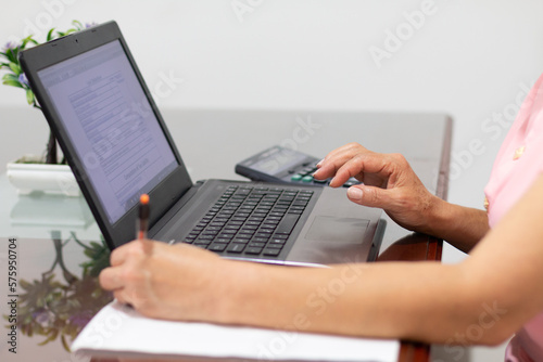 Busy hands: Multitasking woman doing her taxes from her laptop.