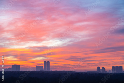 colorful cloudscape over city park and towers at cold dawn