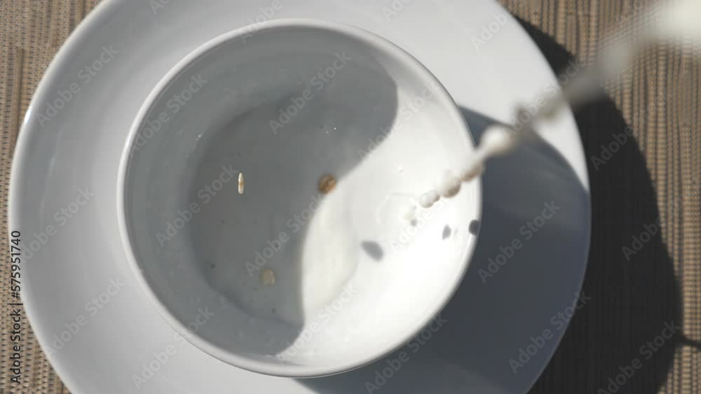 Top view of fresh milk and dry crispy cereal pouring into bowl. Close up of bowl with tasty healthy breakfast. Healthy food concept. Slow motion Top view of fresh milk and dry crispy cereal pouring into bowl. Close up of bowl with tasty healthy breakfast. Healthy food concept. Slow motion