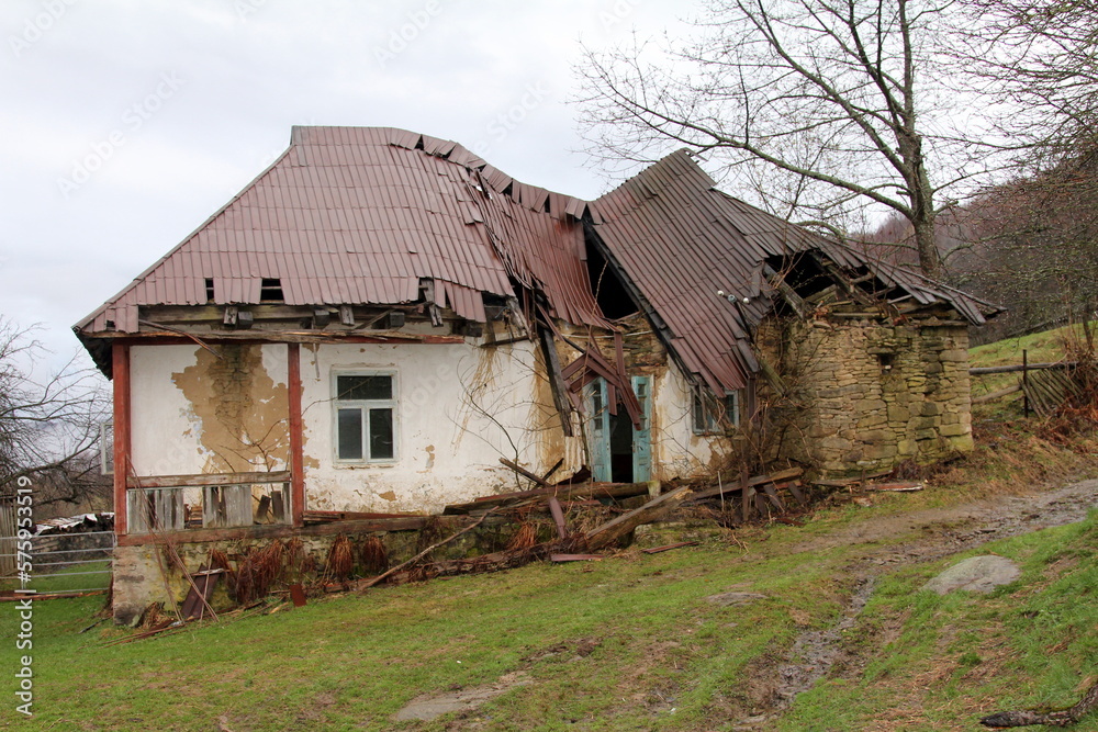 Time destroys an abandoned clay house in a mountain village in the Carpathians of Ukraine, failed roof, cracked walls, globalization, population migration