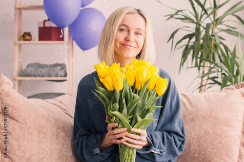 Happy adult woman hold bouquet of flowers at home