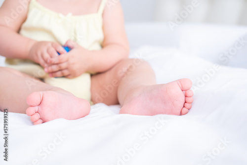 Close up kid child barefooted legs feet lying on white bed linen