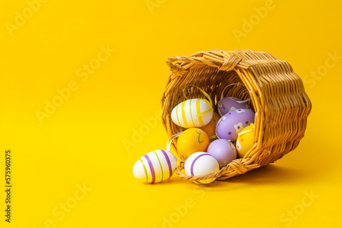 Easter eggs in a wicker basket on a yellow background
