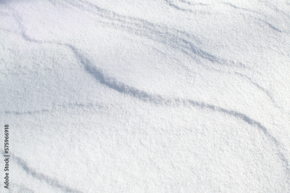 winter background with snowy ground. Wind sculpted patterns on snow surface.