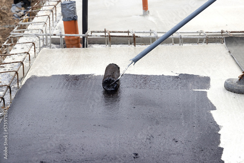 Worker applying a bituminous primer on a Concrete Slab Before Waterproofing photo