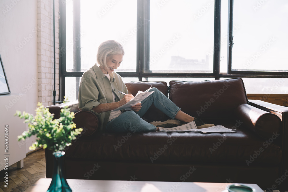 Happy lady writing in papers on couch Happy lady writing in papers on couch