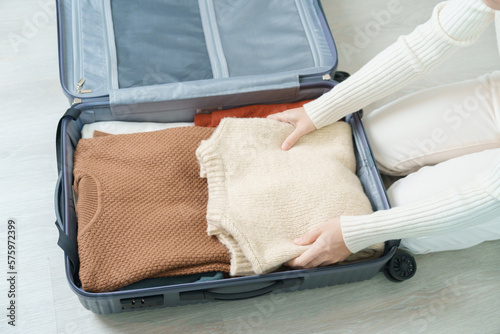 Woman hand packing her winter clothes in luggage. Time to travel, trip, Relax, spring or autumn or winter season and vacation concepts