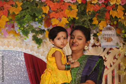 South asian hindu religious young mother holding her little cute daughter in a family celebration 