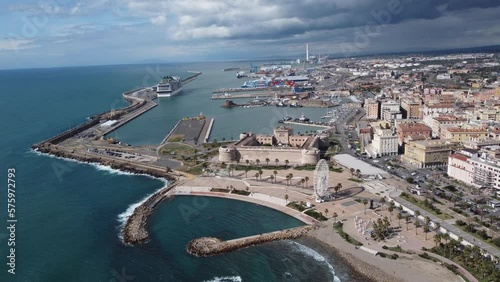 Panoramic view of the city of Civitavecchia with the adjoining tourist port and Forte Michelangelo. Emerald sea and view with tropical palm trees. Ferris wheel and cloudy sky.