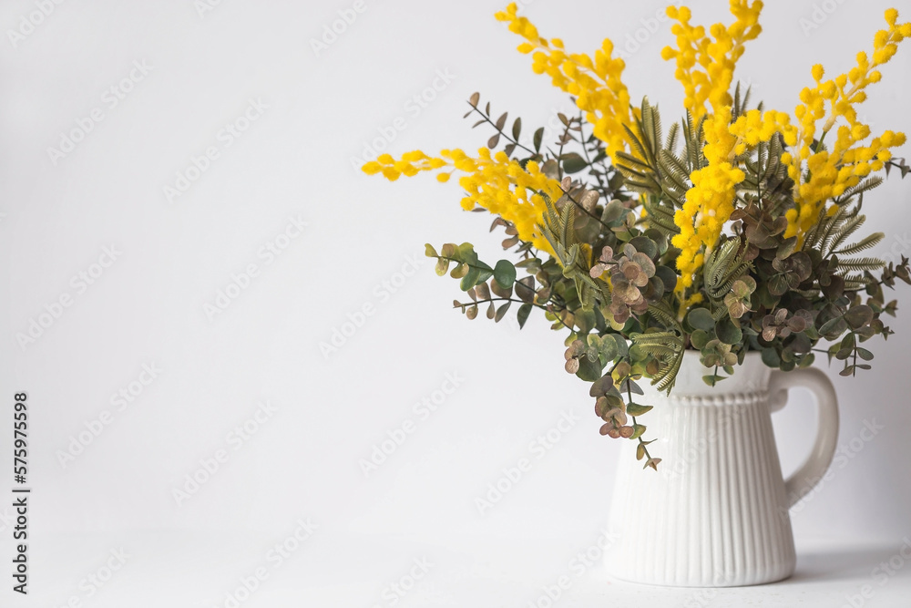 Bouquet of mimosa in a white vase on a white background. The concept of home comfort. The concept of spring in the house and International Women's Day on March 8.