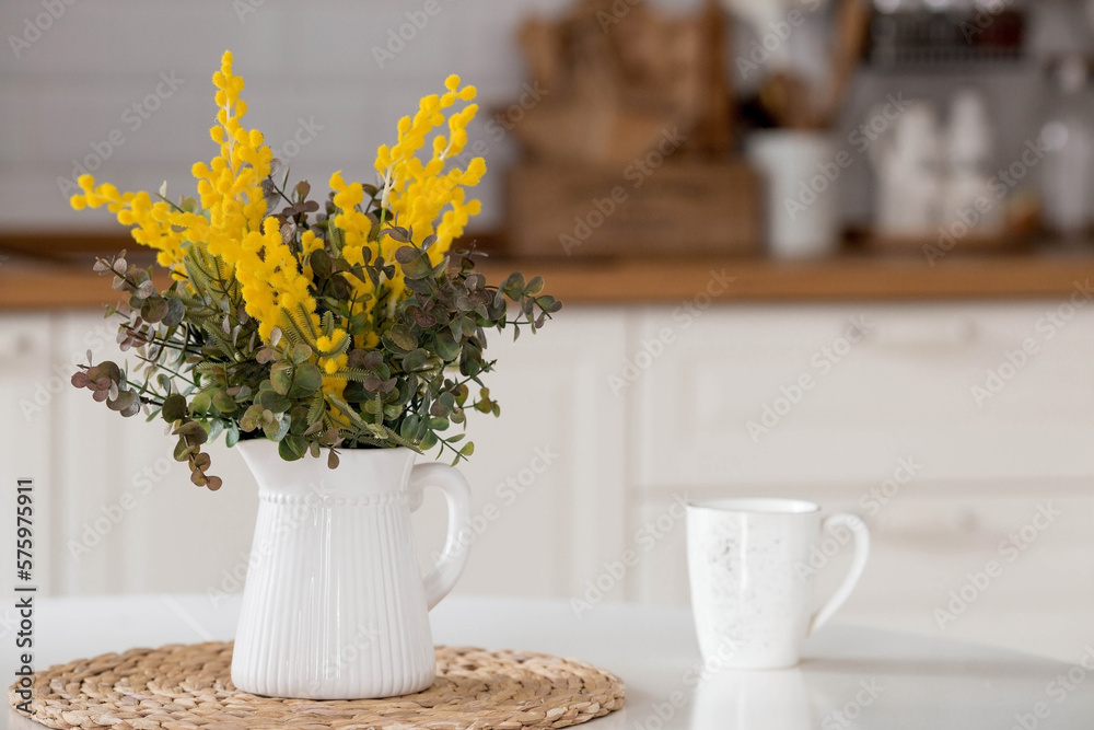 custom made wallpaper toronto digitalA bouquet of mimosa on a white table. In the background, the interior of a white Scandinavian-style kitchen. The concept of home comfort. The concept of International Women's Day on March 8.