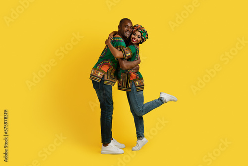 Lovely African couple in national costumes embracing on yellow
