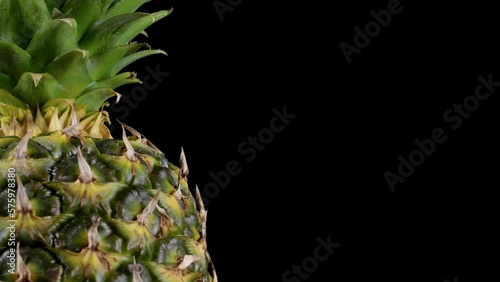 A delicious pineapple rotating on the left side against a black background.