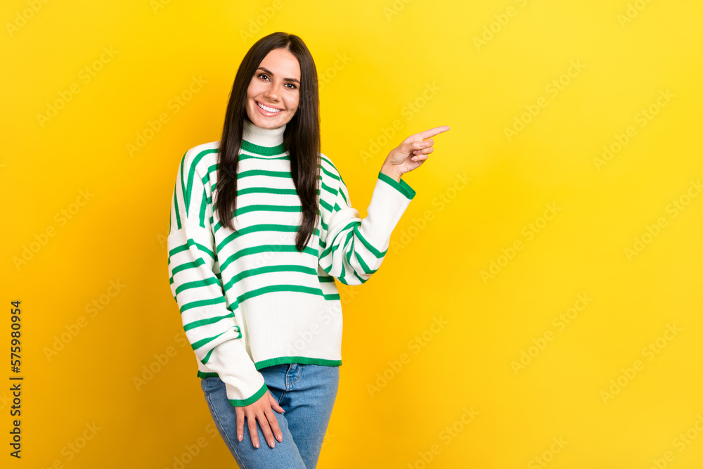 Photo of sweet shiny woman wear striped sweater showing finger empty space isolated yellow color background Photo of sweet shiny woman wear striped sweater showing finger empty space isolated yellow color background