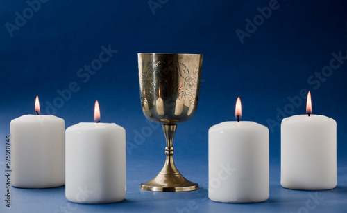 beautiful christian chalice surrounded by candles and blue background