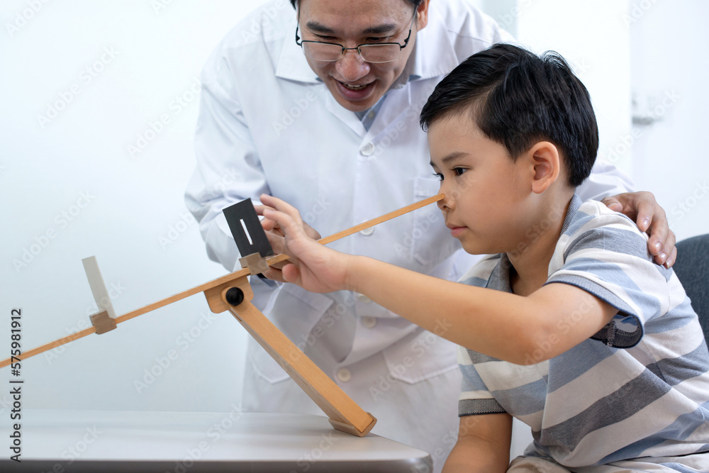 Asian optometrist uses a device to check the vision of child boy at an ophthalmology clinic Asian optometrist uses a device to check the vision of child boy at an ophthalmology clinic