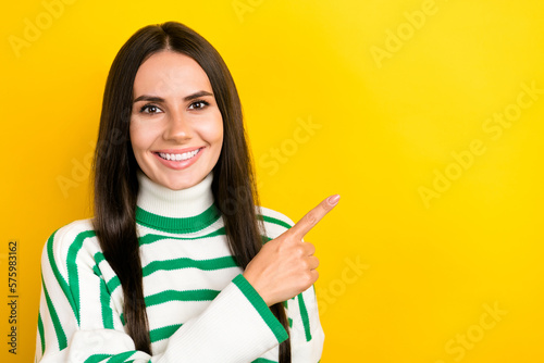 Photo of cute adorable woman wear striped sweater pointing finger empty space isolated yellow color background