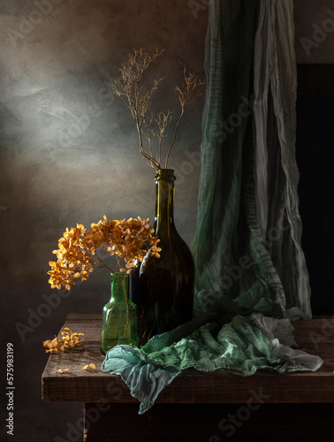 Modern still life with dry hydrangea and green tippet on a dark background photo